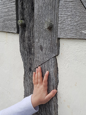 Child's hand on the exterior timber frame of Langley Gatehouse