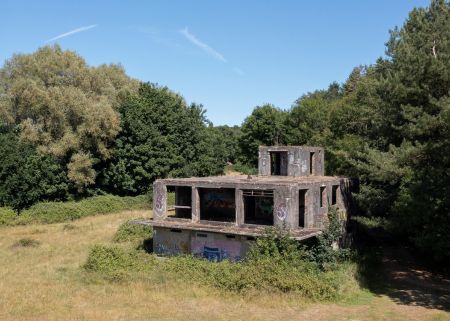 A derelict concrete building surrounded by trees and grass