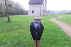 A black box on a wooden post which charges electronic cars