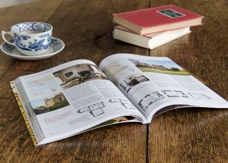Landmark Trust handbook open on wooden table beside a teacup and saucer