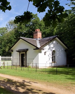 A small white lodge surrounded by gardens