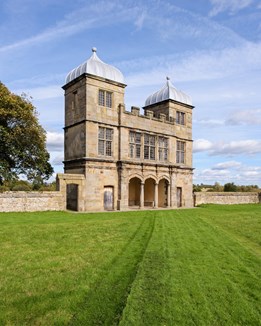 A folly with two towers overlooking a green
