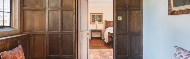 View through a door in a wood panelled wall to a bedroom