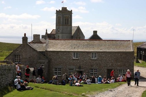 A grey stone building with people sitting outside