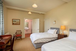 Twin bedroom with open door through to ensuite bathroom