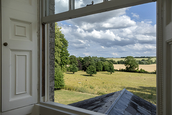 Views through the window at Cavendish Hall to rolling green hills and countryside