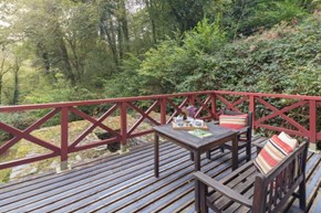 A table and chairs on a wooden decking surrounded by trees
