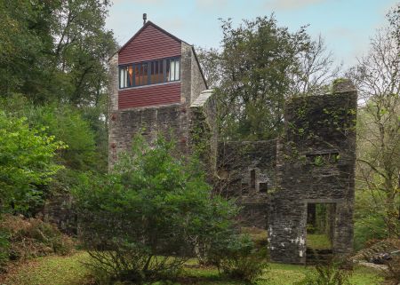 A tall brick building with a large window surrounded by trees with green leaves