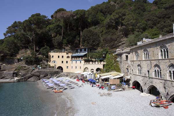 Beach surrounded by historic arched buildings with trees behind