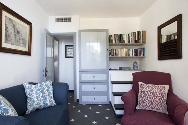 Sitting room with sofa and chair and steps up to shelves with books