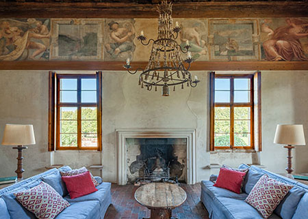 Historic sitting room with painted frescos and two sofas beside a fire place