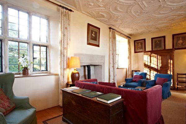 A living room with blue and red sofas and oil paintings on the wall