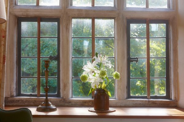 A vase of white lilies and green foliage on a windowsill 