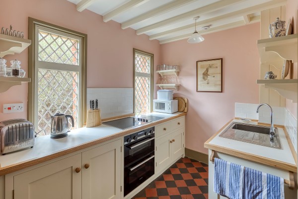 The interior of the kitchen at Keeper's Cottage. With pale pink walls and cream cabinets.