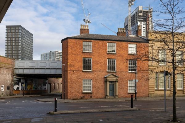 Exterior of a red brick building with a trainline in the background