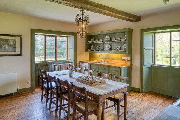 A wooden dining table and cabinets painted light green