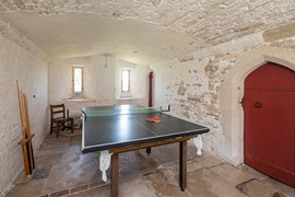 Whitewashed cellar with wooden door and table tennis table in the centre
