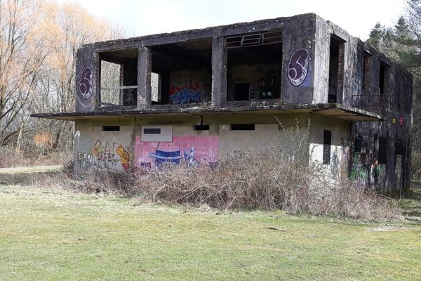 A derelict grey building covered in graffiti