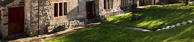 A grassy bank outside a stone building with a red door