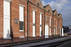A red brick building on the edge of a train track